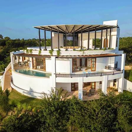White private coastal villa surrounded by tropical greenery
